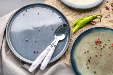 Gri arkaplanda tabaklar, kaşıklar ve karabiberlerle kompozisyon