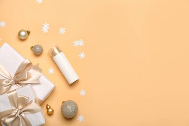 Kozmetik ürün şişesi, Noel hediyeleri ve renk arkaplan süslemeleri içeren kompozisyon