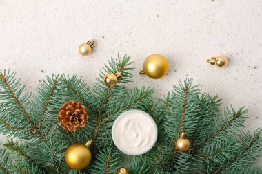 İçinde krema kavanozu, Noel topları ve arka planda köknar dalları olan kompozisyon