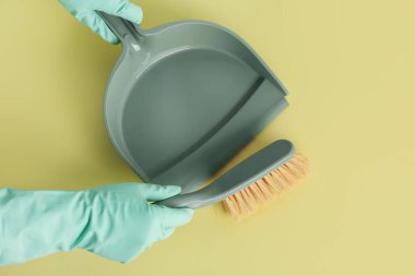 Yeşil arka planda faraş ve fırçayla lastik eldivenli kadın elleri