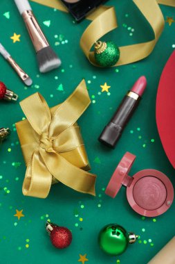 Kozmetik ürünleri, Noel hediyesi ve yeşil arka planda süslemeler.