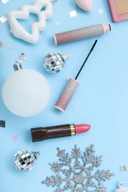 Açık mavi arka planda kozmetik ve Noel süslemeleri ile kompozisyon