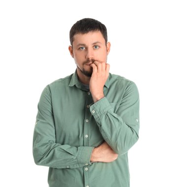 Beyaz arka planda tırnaklarını yiyen gömlekli yakışıklı bir adam.