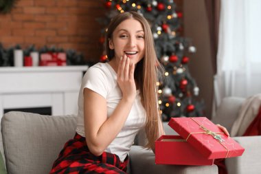 Noel arifesinde evde pijamalı genç bir kadın açılış hediyesi.