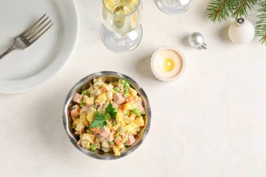 Bir kase lezzetli Olivier salatası, yanan mum ve arka planda bir bardak şampanya.