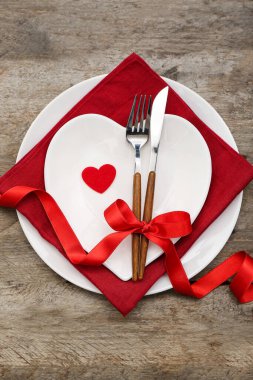 Ahşap arka planda yay ve kalplerle Sevgililer Günü için masa ayarlayın.