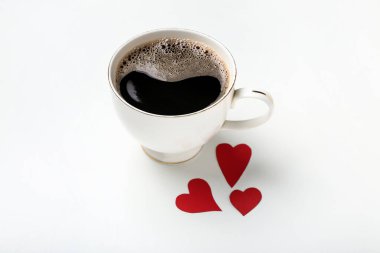 Beyaz zemin üzerinde kırmızı kalpler olan bir fincan kahve. Sevgililer Günü kutlaması