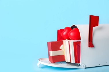 Zarflı posta kutusu, mavi arka planda hediye ve kalp. Sevgililer Günü kutlaması