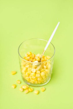 Yeşil zemin üzerinde kaşık ve mısır taneleri olan cam.