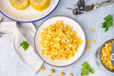 Lezzetli mısır, maydanoz yaprakları, teneke kutu ve gri masada açacağı olan tabaklar.