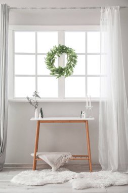 Penceresinde ve masasında Noel çelengi olan oturma odasının içinde.