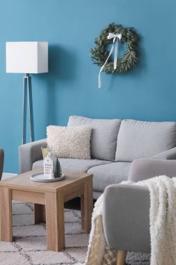 İçinde Noel çelengi, kanepe ve lamba olan oturma odası.