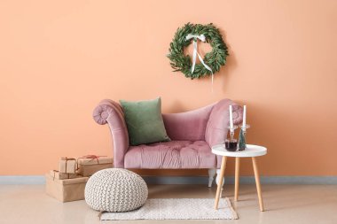 Oturma odasının içinde Noel çelengi, koltuk ve masa var.