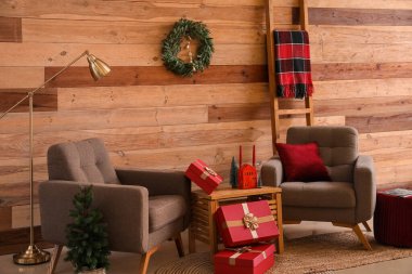 Oturma odasının içinde Noel çelengi, koltuk ve hediyeler var.