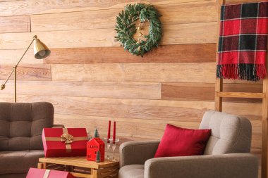 Oturma odasının içinde Noel çelengi, koltuk ve hediyeler var.