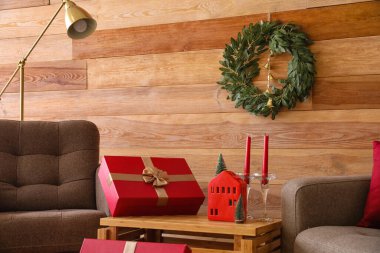 Oturma odasındaki ahşap duvarda çanlar asılı Noel çelengi