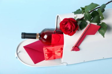 Posta kutusu, bir şişe şarap, gül ve hediye mavi arka planda. Sevgililer Günü kutlaması