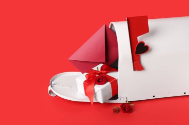 Posta kutusu, kırmızı arka planda güller ve hediye. Sevgililer Günü kutlaması