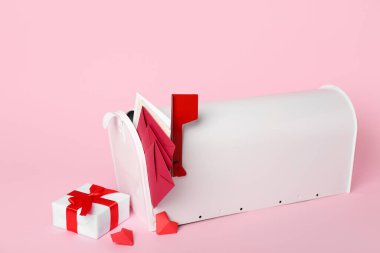 İçinde mektuplar, kalpler ve pembe arka planda hediyeler olan posta kutusu. Sevgililer Günü kutlaması