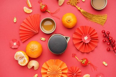 Fincanlı çaydanlık, mandalina, fal kurabiyeleri ve kırmızı arka planda Çince semboller. Yeni yıl kutlaması