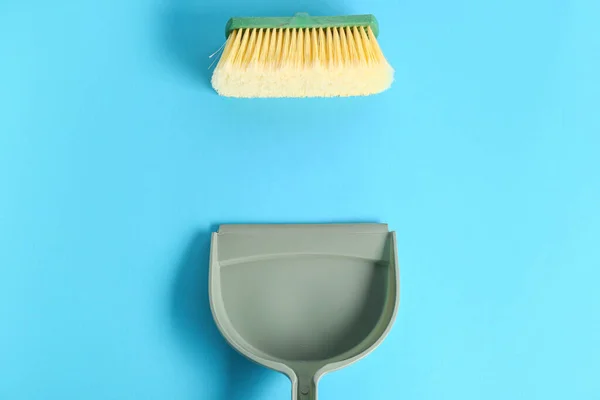 Dustpan with cleaning brush on color background