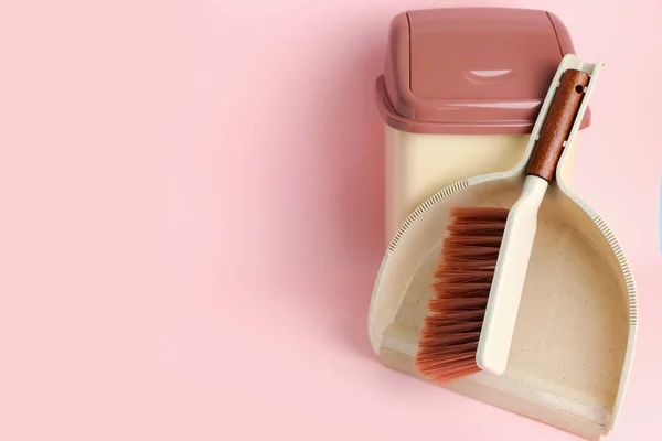 Cleaning brush, dustpan and rubbish bin on pink background