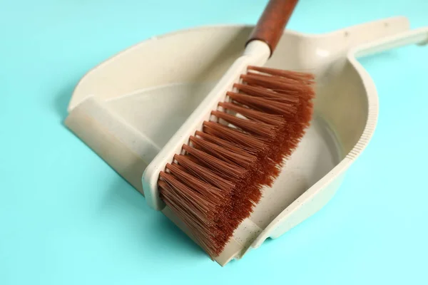Cleaning brush and dustpan on color background, closeup