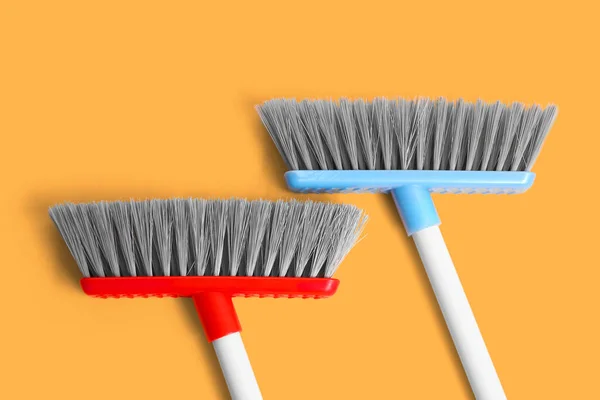 Cleaning brooms on color background, closeup