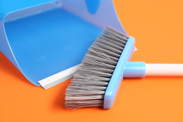 Cleaning broom and dustpan on color background, closeup
