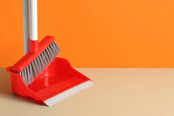 Dustpan with cleaning broom on floor near color wall