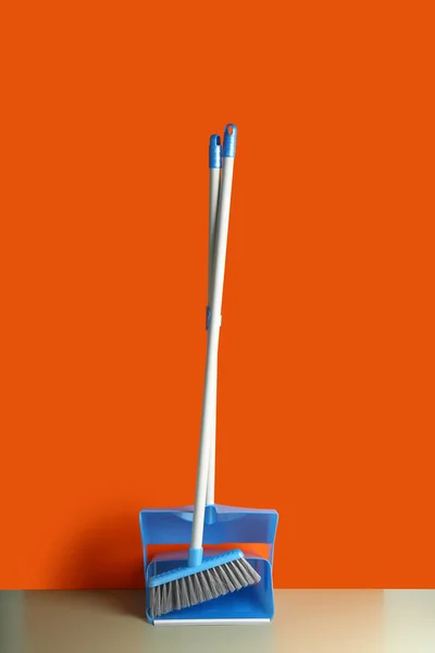 Dustpan and cleaning broom on floor near color wall