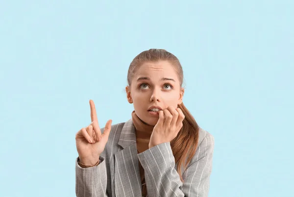 Young Businesswoman Biting Nails Pointing Something Blue Background — Stock Photo, Image
