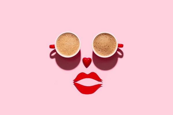 Face made of coffee cups, heart and paper lips on pink background. Valentine's Day celebration