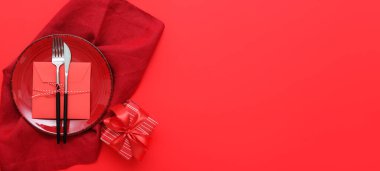 Kırmızı zemin üzerinde Sevgililer Günü için şık masa ayarları ve hediye paketleri.