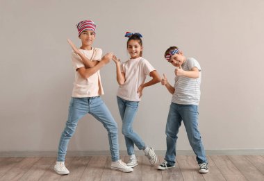 Küçük mutlu arkadaşlar gri duvarın yanında el kol geziyor.