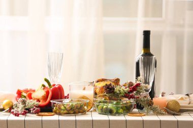 Yemek odasındaki pencerenin yanında köknar dalları olan Noel masası.