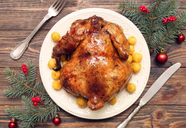 Lezzetli fırında tavuk, köknar dalları ve ahşap arka planda Noel süslemeleri içeren kompozisyon