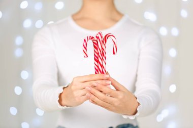 Bulanık Noel ışıklarına karşı lezzetli şeker kamışları tutan kadın.