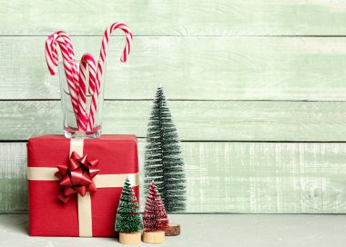 Noel hediyesi, baston şekerli cam ve masa üzerindeki Noel süsü renkli ahşap arka plan