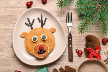 Lezzetli ren geyiği gözlemeleri, köknar dalları ve ahşap arka planda Noel süslemeleri olan tabaklar.