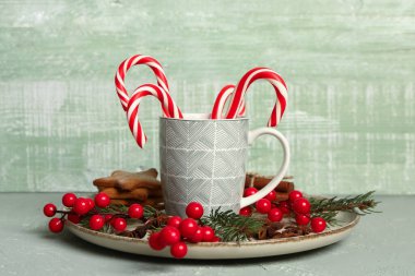 Bir fincan lezzetli baston şekerler, Noel süsü, masada kurabiye ve baharatlar.