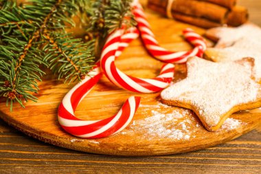 Şeker kamışlı tabaklar, Noel kurabiyeleri ve ahşap masada köknar dalları, yakın plan.