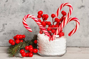 Lezzetli baston şekerli cam kavanoz, kar, Noel dekoru ve masa üzerinde grunge arka planına karşı köknar dalları