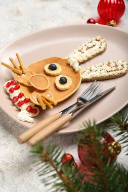 Krep, meyve ve Noel dekorundan yapılmış tavşanlı tabaklar grunge masasında, yakın plan