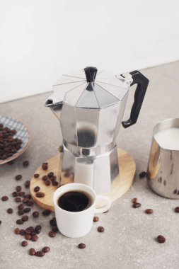 Gayzer kahve makinesi, bir fincan espresso, açık arkaplanda süt ve fasulye.