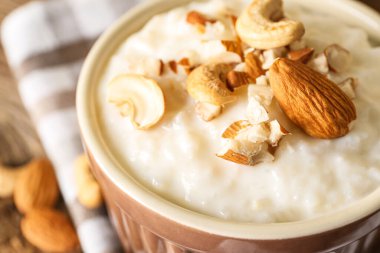 Tahta masada lezzetli sütlaç, kaju ve badem fıstıklı kase, yakın plan.