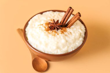 Lezzetli sütlaç, tarçın, anason ve kaşık ile bej arka planda