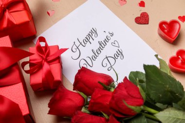 Yazılı kart Mutlu VALENTINE Günü, bej arka planda güller ve hediyeler, yakın plan