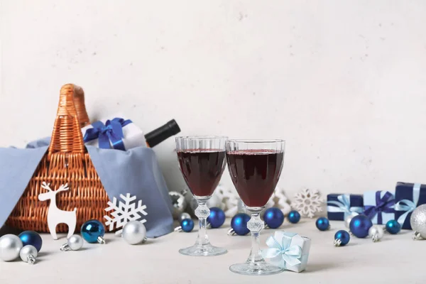 Glasses of red wine with Christmas gift on white table, closeup