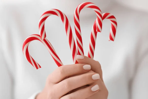 Woman holding sweet candy canes, closeup